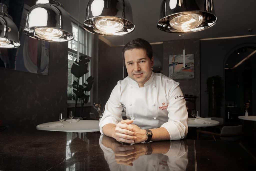 Photo of Rafael Cagali sitting behind a table with his fingers crossed on it